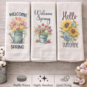 May include: Three white waffle-weave dish towels with floral designs and text. One towel says "Welcome Spring" with tulips in a watering can. Another says "Welcome Spring" with tulips in a bucket. The third says "Hello Sunshine" with sunflowers.