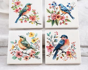 May include: A set of four square ceramic coasters, each featuring a watercolor painting of a bird perched on a floral branch. The coasters measure 4x4 inches and have a glossy finish. The text on the image says "4x4 Inch Ceramic Coaster Set".