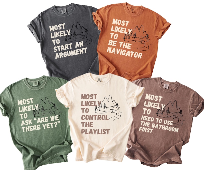 May include: Five short-sleeved t-shirts in various colors, each with a unique phrase in white text and a mountain and river graphic. The phrases include "Most Likely to Start an Argument" and "Most Likely to Be the Navigator."