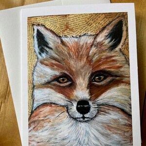 May include: Close-up of a fox's face painted in a realistic style. The fox has orange fur, a white muzzle, and black eyes. The background is a collage of old book pages.
