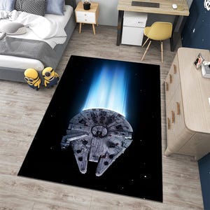Peut inclure: Un tapis rectangulaire avec une illustration détaillée du vaisseau spatial Millennium Falcon sur fond noir. Le tapis présente un effet de lumière bleue émanant du vaisseau, créant un visuel dynamique.