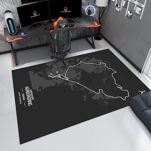 May include: A black and white map of the N&uuml;rburgring race track, with the text "N&uuml;rburgring" and "Nordschleife" printed on the map. The map is printed on a black rug.