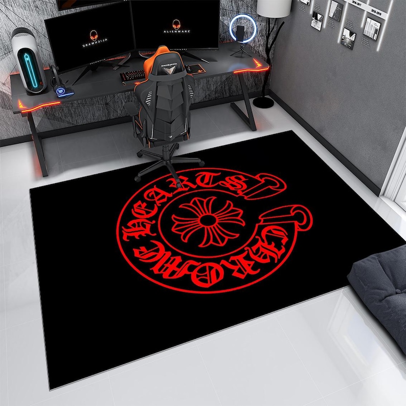 May include: A rectangular area rug featuring a black background with a large, circular red graphic in the center. The design includes a stylized cross symbol surrounded by text that reads CHROME HEARTS in a bold, gothic-inspired typeface.