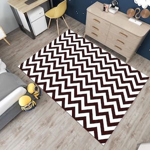 May include: A white and brown chevron patterned area rug. The rug has a geometric design with alternating white and brown zigzags.