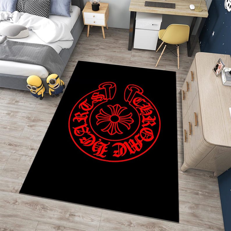 May include: A rectangular area rug featuring a solid black background with a large, circular red graphic in the center. The design includes the text "CHROME HEARTS" in a gothic font encircling a stylized cross symbol within the red circular border.