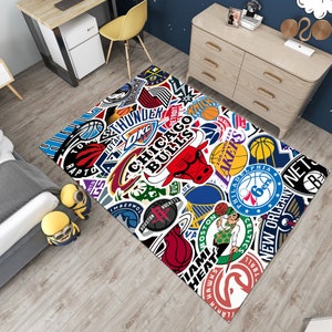 May include: A white and colorful rug with various NBA team logos, including the Chicago Bulls, Los Angeles Lakers, and Philadelphia Sixers. The rug features a white background with colorful team logos and names.