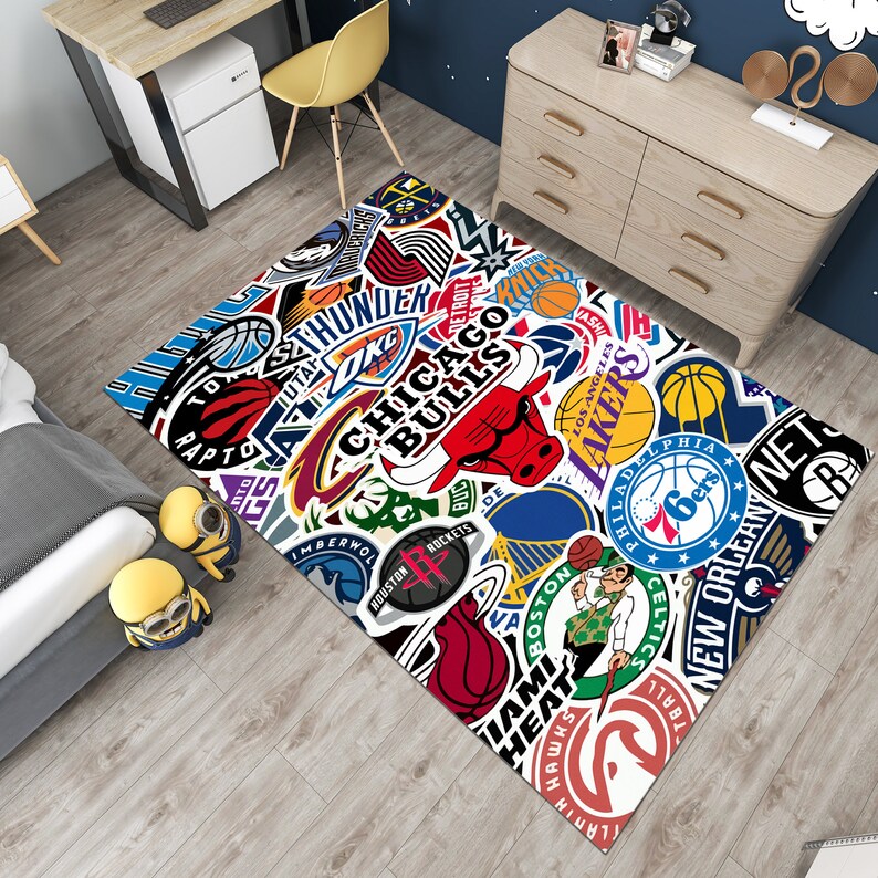 May include: A white and colorful rug with various NBA team logos, including the Chicago Bulls, Los Angeles Lakers, and Philadelphia Sixers. The rug features a white background with colorful team logos and names.