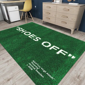 May include: Green rug with the text "SHOES OFF" in white lettering. The rug also includes the text "IKEA&reg;c/o Virgil Abloh&trade; Flooring, Almhult Sweden c 2019" in white lettering.