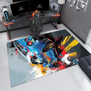 May include: A rectangular area rug featuring a vibrant, abstract graphic of a blue sports car. The design incorporates dynamic paint splatters in shades of yellow, red, and black against a light gray background, creating a high-contrast visual effect.
