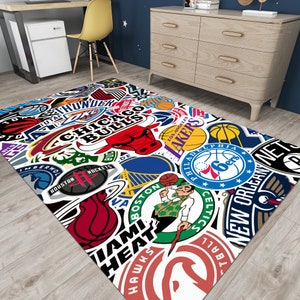 May include: A white area rug with a colorful collage of NBA team logos, including the Chicago Bulls, Los Angeles Lakers, Boston Celtics, Miami Heat, and New Orleans Pelicans.