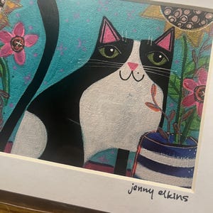 May include: A framed art print featuring a whimsical black and white cat with green eyes, set against a turquoise background with floral accents. The cat is positioned near a blue and white striped vase. The artist's signature, "jenny elkins," is visible.