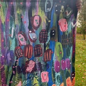 May include: Abstract art tapestry with a colorful, textured design featuring pink, blue, green, orange, and black. The tapestry has a vertical orientation and is made of fabric.