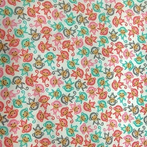 May include: A white fabric featuring a repeating pattern of small cartoon monkeys in shades of pink, teal, and gray. Each monkey has a smiling face, rounded ears, and a long tail, arranged in a dense, multi-directional layout across the surface.