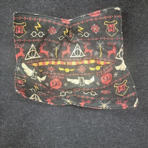 May include: A black bowl cozy with a quilted pattern featuring red and gold Harry Potter-themed icons. The design includes lightning bolts, glasses, deer, and the Hogwarts crest. The words "Platform 9 3/4" are also visible.
