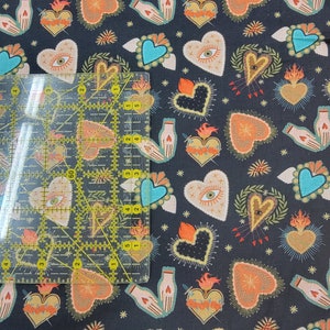 Puede incluir: Tela negra con un patr&oacute;n repetido de corazones, manos y estrellas de colores. Los corazones est&aacute;n rodeados de llamas y tienen una variedad de dise&ntilde;os, que incluyen ojos, espadas y flores.
