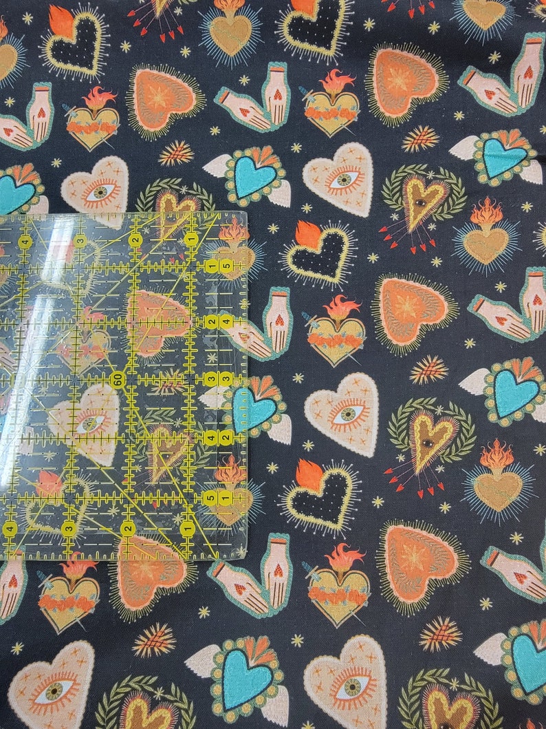 Puede incluir: Tela negra con un patr&oacute;n repetido de corazones, manos y estrellas de colores. Los corazones est&aacute;n rodeados de llamas y tienen una variedad de dise&ntilde;os, que incluyen ojos, espadas y flores.