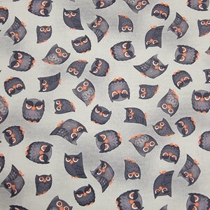 May include: A repeating pattern of cartoon owls in various poses. The owls are primarily gray with orange accents and white eyes, set against a light gray background. The design is whimsical and suitable for fabric or wallpaper.