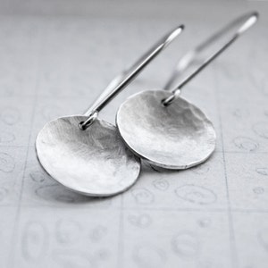 May include: A pair of silver dangle earrings with hammered round disc pendants.