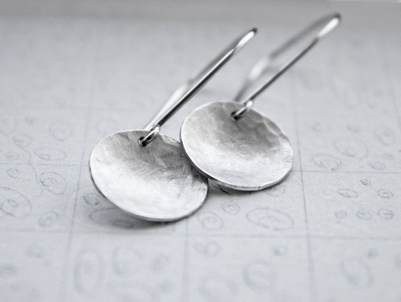 May include: A pair of silver dangle earrings with hammered round disc pendants.
