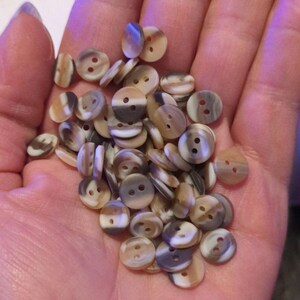 May include: A collection of brown and white striped buttons with two holes each.