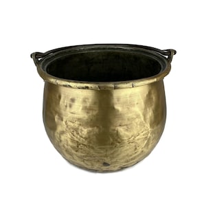 Puede incluir: Un caldero de latón antiguo grande con dos asas. El caldero tiene un acabado martillado y un fondo redondeado.