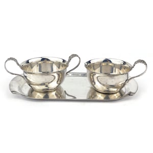 May include: A silver serving tray with two silver bowls with handles. The bowls are round and have a smooth, polished finish.