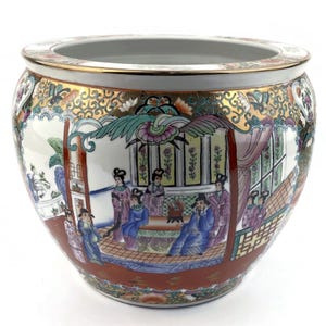 Könnte beinhalten: Ein runder, weißer Keramik-Pflanztopf mit einer breiten Öffnung und einem goldenen Rand. Der Pflanztopf zeigt eine detaillierte, farbenfrohe, asiatisch inspirierte Szene mit Figuren in traditioneller Kleidung. Das Design umfasst goldene Akzente und einen roten Sockel.
