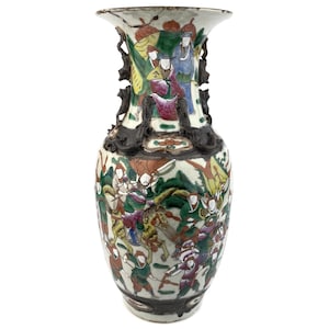 Puede incluir: Un jarrón chino antiguo con un borde acampanado y obras de arte detalladas. El jarrón presenta una escena pintada de figuras con atuendos coloridos, con detalles y asas oscuras. El diseño incluye figuras a caballo y en batalla.