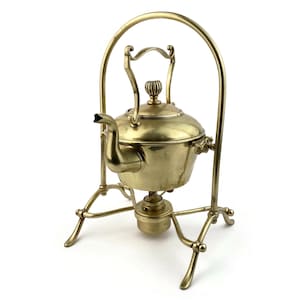 May include: A brass kettle with a stand and a built-in burner. The kettle has a curved handle and a spout. The stand has three legs and a round base.