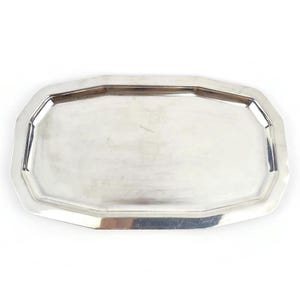 May include: A silver-coloured, octagonal serving tray. The tray has a reflective surface and a slightly raised edge. The shape is a modified rectangle with eight sides. The tray is likely made of metal and is suitable for serving food or displaying items.