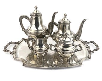 May include: A silver tea set with a teapot, creamer, sugar bowl, and tray. The set is ornate with detailed designs and a polished finish.