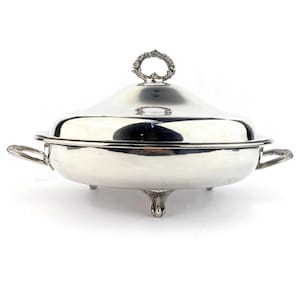 Peut inclure: Un plat de service argenté avec un couvercle et des poignées. Le plat a une forme arrondie, trois pieds décoratifs et une poignée sur le couvercle. La poignée du couvercle est un anneau décoratif. Le plat est conçu pour servir des aliments.