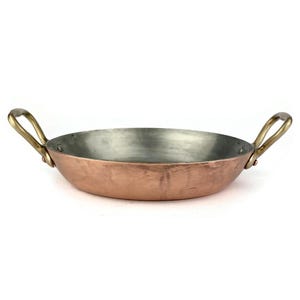 May include: An oval copper serving dish with two brass handles. The dish has a hammered finish.