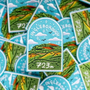May include: A blue and green embroidered patch with the text "Ingleborough 723m" and a stylised illustration of a mountain with a red and orange peak.