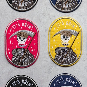 May include: Four embroidered patches featuring a skeleton in a hooded cloak holding a scythe. The patches are yellow, red and blue with white text that reads "It's Grim Up North".