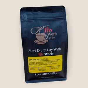 His Word Coffee Breakfast Blend 12 oz bag photographed straight-on against a light background, showing the full front label with the His Word Coffee logo, Start Every Day With His Word, the yellow Breakfast Blend panel listing caramel and mellow dark chocolate flavor notes with clean fruit-like sweetness, process Natural and Washed, roast level Med/Light, and Specialty Coffee