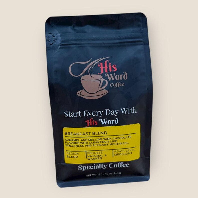 His Word Coffee Breakfast Blend 12 oz bag photographed straight-on against a light background, showing the full front label with the His Word Coffee logo, Start Every Day With His Word, the yellow Breakfast Blend panel listing caramel and mellow dark chocolate flavor notes with clean fruit-like sweetness, process Natural and Washed, roast level Med/Light, and Specialty Coffee