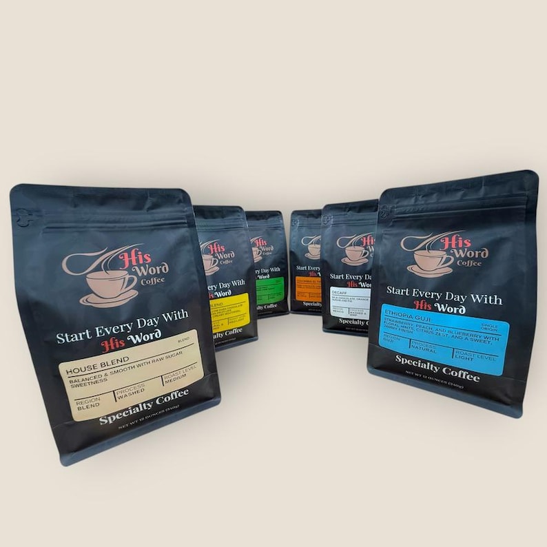 Five His Word Coffee 12 oz bags arranged in a fan display on a neutral background, showing different blends and origins with colored product labels including House Blend with tan label, and Ethiopia Guji with blue label among others, each displaying the His Word Coffee logo and Specialty Coffee branding