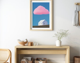 May include: A framed art print featuring a white house under a pink cloud against a blue sky. The artwork is displayed on a white wall above a wooden bench with woven baskets and a rattan chair, creating a minimalist aesthetic.