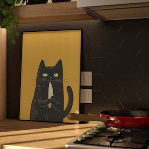 May include: An illustration of a black cat holding a knife, printed on a yellow background, framed in black. The print is hanging on a wall in a kitchen setting.