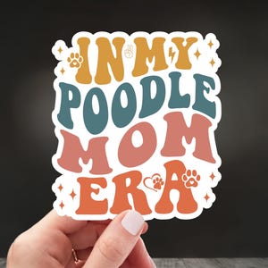 May include: A white sticker with the text "In My Poodle Mom Era" in colorful retro-style lettering. The sticker features paw prints, a heart, and a peace sign.