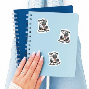 May include: A light blue notebook with spiral binding and a light blue notebook with three stickers that say "Oops! I Got Another Plant!" The stickers feature a goose with plants.