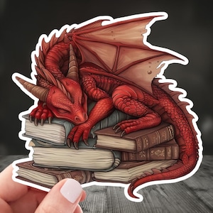 May include: A red dragon with wings curled up asleep on top of a stack of old books.