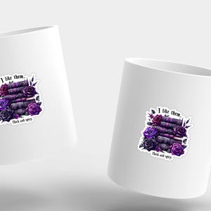 K&ouml;nnte beinhalten: Wei&szlig;e Keramiktasse mit einer lila und schwarzen Illustration eines Stapels B&uuml;cher mit Blumen und dem Text "Ich mag sie. Dick und w&uuml;rzig."