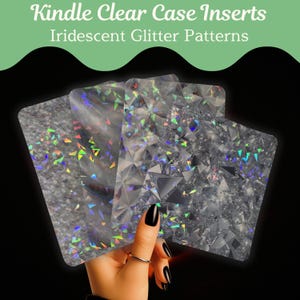 May include: Kindle clear case inserts with iridescent glitter patterns. The inserts are held in a hand with black nail polish. The inserts have a clear base with a variety of glitter patterns, including a textured, a geometric, and a scattered design.