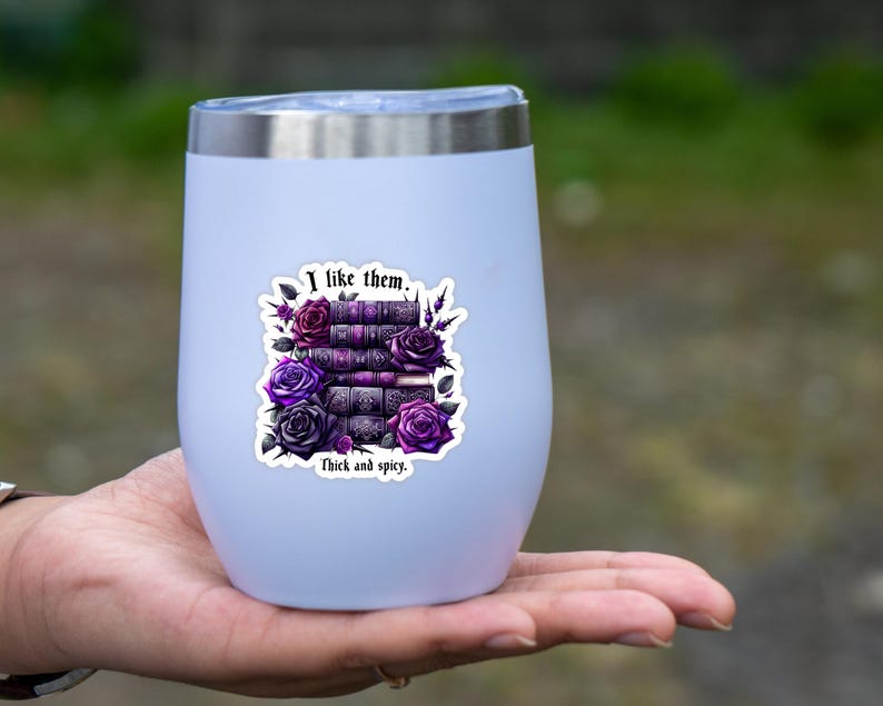 K&ouml;nnte beinhalten: Ein wei&szlig;er Edelstahlbecher mit einem Aufkleber, auf dem "I like them. Thick and spicy." steht. Der Aufkleber zeigt einen Stapel B&uuml;cher mit violetten und schwarzen Rosen.