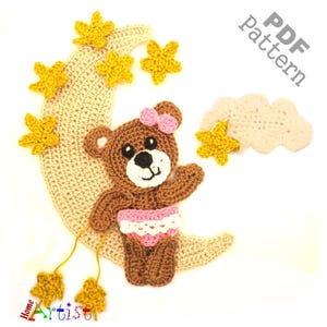 以下が含まれることがあります： 黄色い星がついた三日月に座っている茶色のテディベアのための編み物パターン。パターンには、星がついた雲と、クマの頭にピンクのリボンが含まれています。PDFパターン