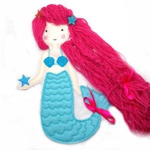 May include: A felt mermaid doll with pink yarn hair, a blue top, and a turquoise tail. The doll is holding a blue star.