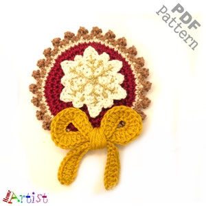 May include: A crocheted Christmas ornament featuring a red and brown circle with a white snowflake in the center and a yellow bow at the bottom. The ornament is perfect for adding a touch of handmade charm to your holiday decor.