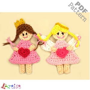May include: Two crocheted dolls, one with a crown and the other with angel wings, both holding pink hearts. The dolls are wearing pink dresses and have brown and yellow hair.